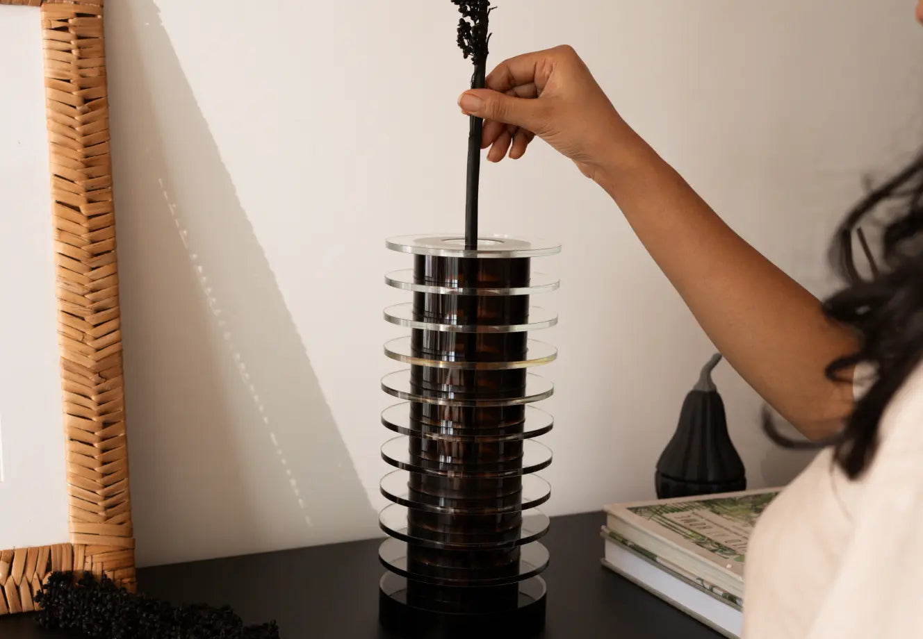 Hand styling a modern black and glass vase on a minimal console table for luxury home decor.