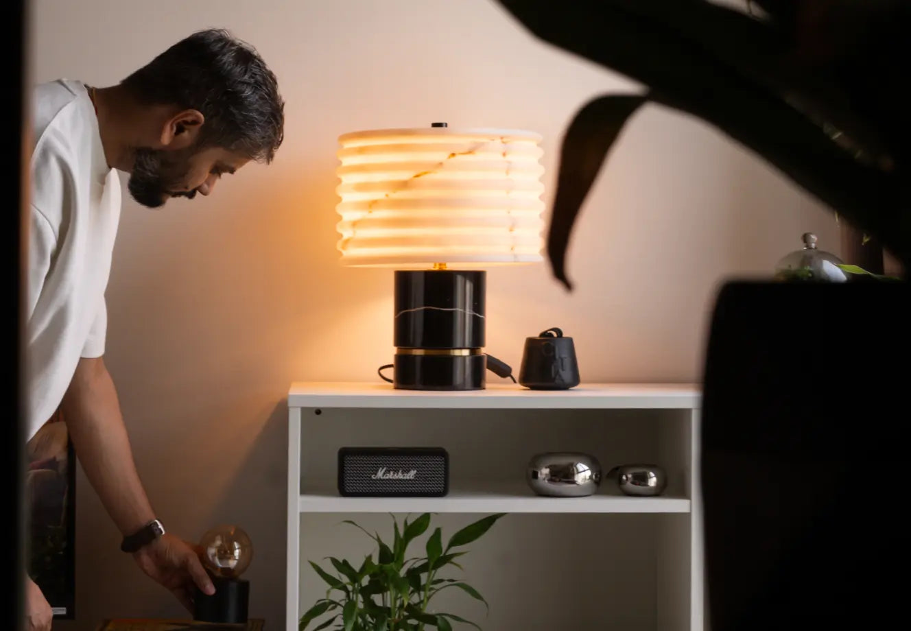 Man styling a warm-lit table lamp on a white shelf for Diwali decor