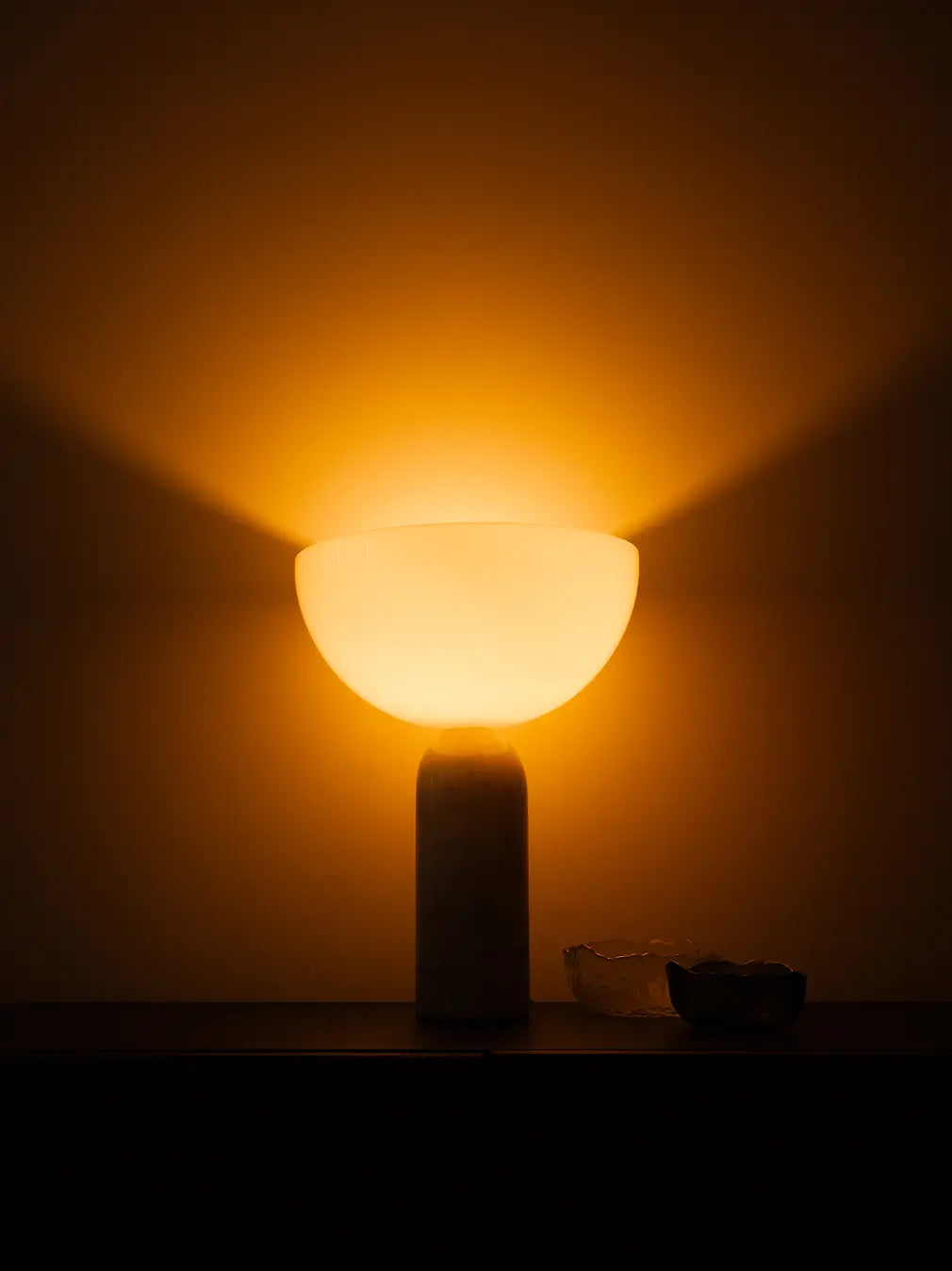 Arc Marble Table Lamp glowing at night with soft ambient light against a wall