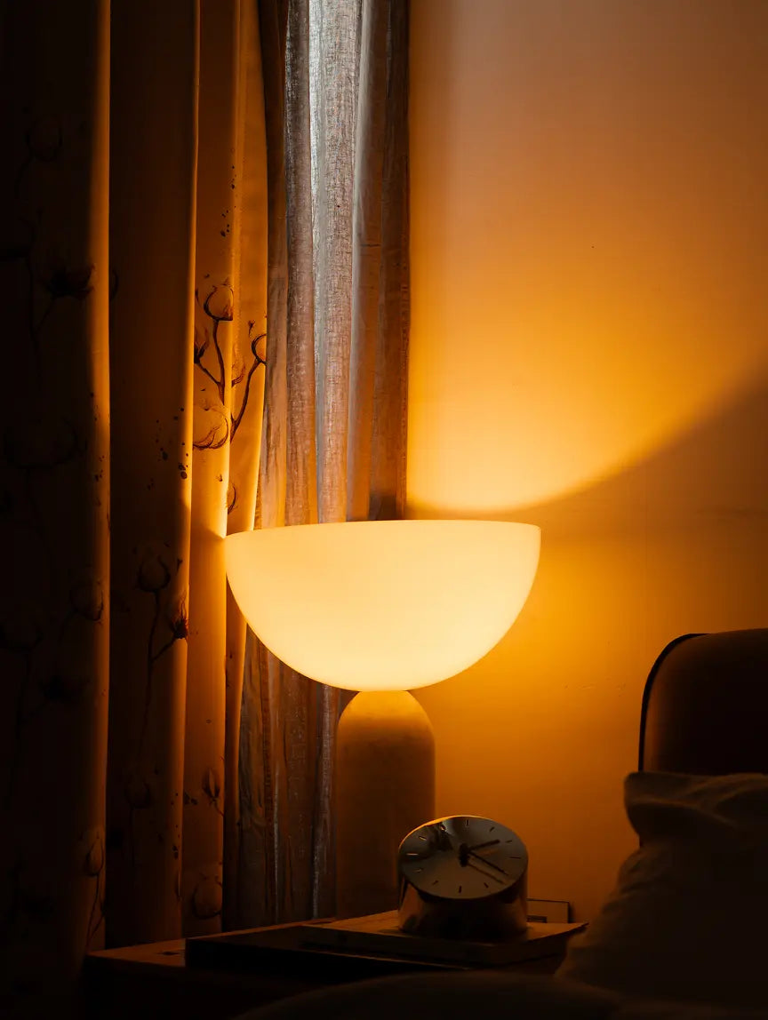 Arc Marble Table Lamp casting warm ambient light on bedside near curtain panel