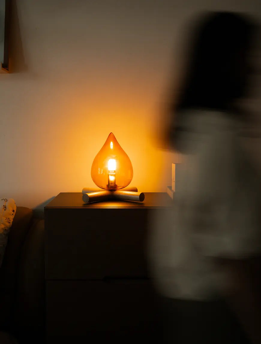 Glowing lamp on a table with a blurred person in the foreground