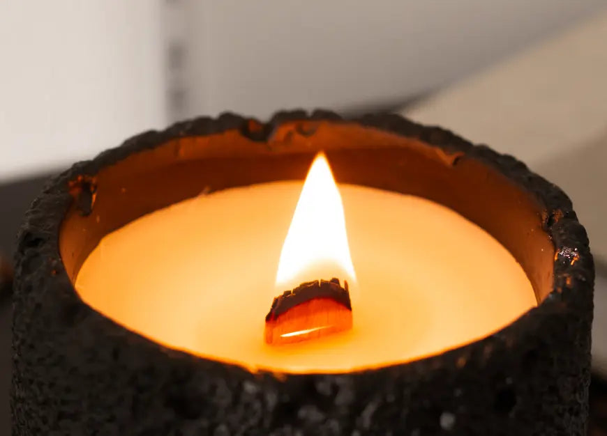 Close-up of wooden wick flame in black concrete candle