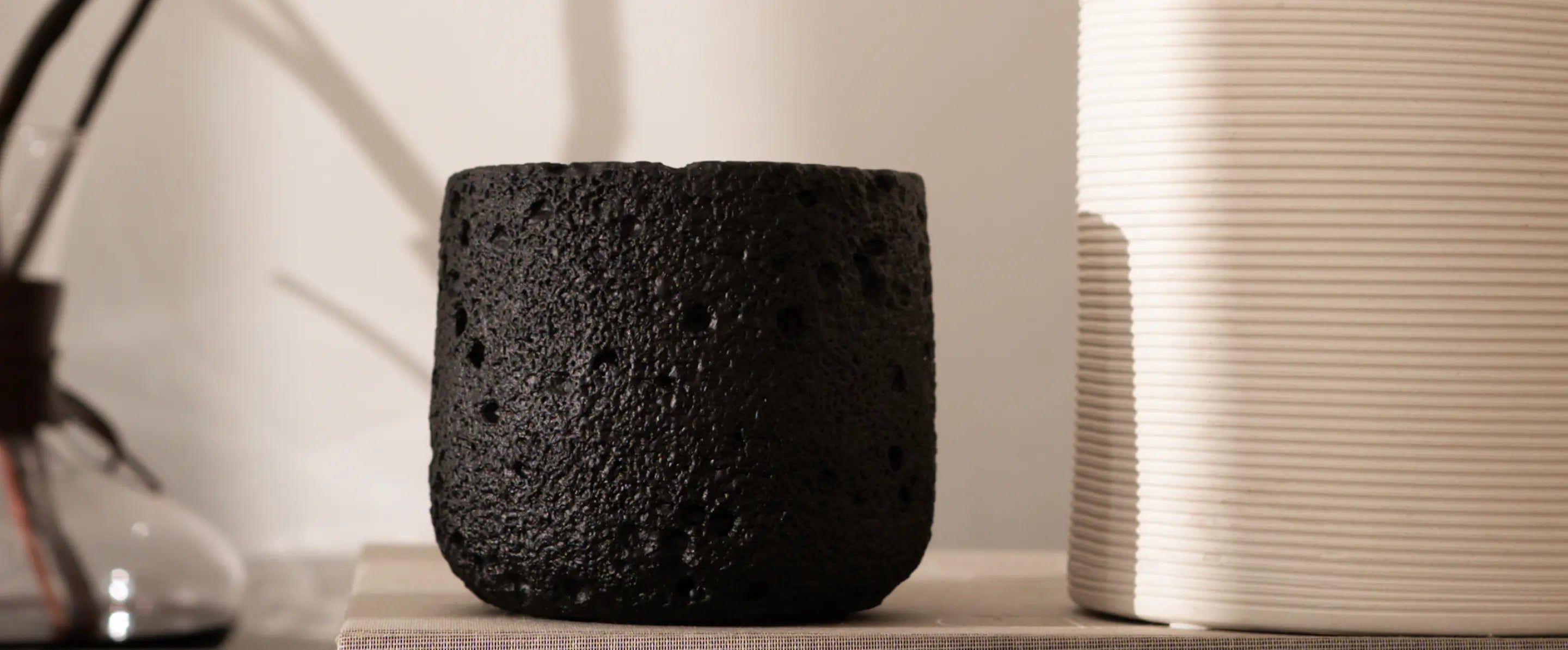 Textured black concrete candle beside white ribbed vase