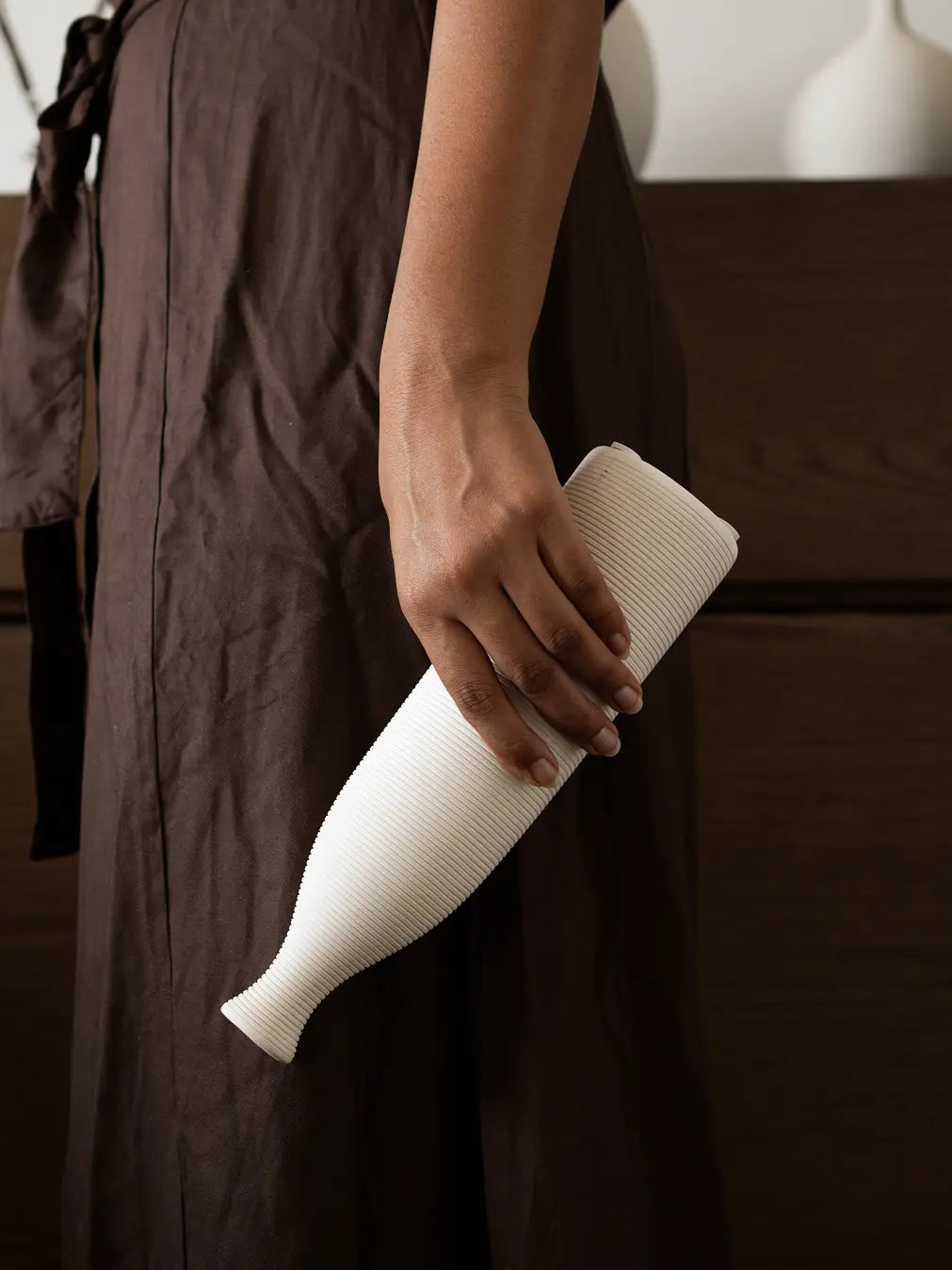 Small Contour Ceramic Vase with a ribbed matte finish, elegantly held against a neutral-toned outfit.