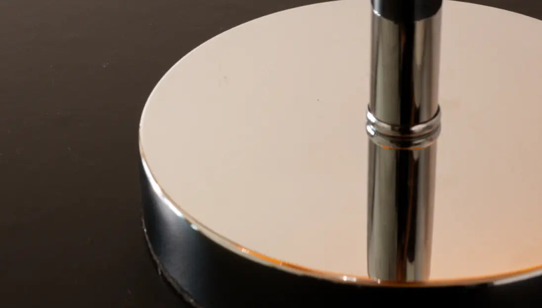 Close-up of a metallic base of Dawn Table Lamp on a wooden surface with a dark background