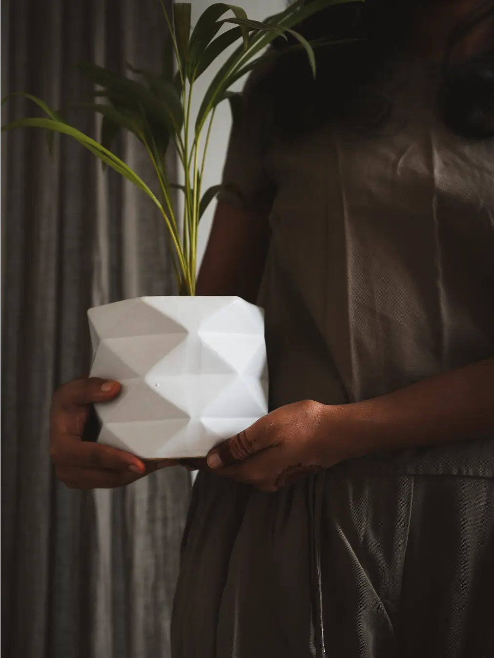 Person holding a white Diamond Ceramic Planter with a vibrant green plant.