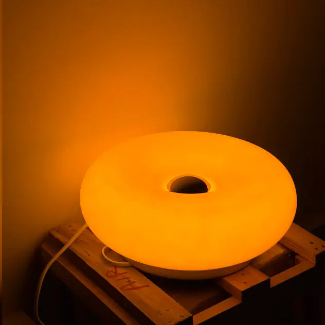Donut Orange Lamp on a wooden pallet against an orange wall.