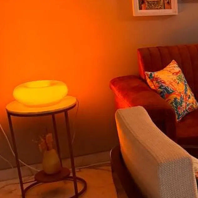 Living room with a red couch, small table with a Donut Lamp, and wall.