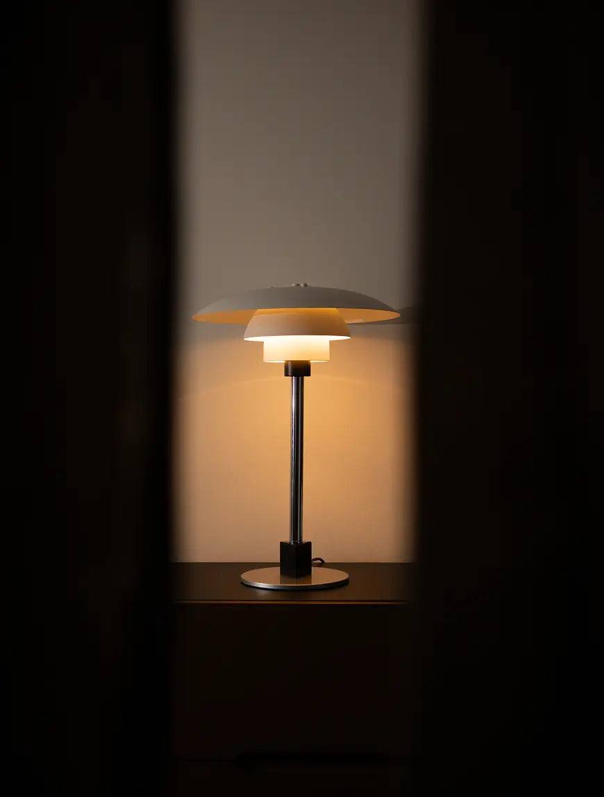 Echo Metal Table Lamp glowing softly with layered shade and silver base in dim room