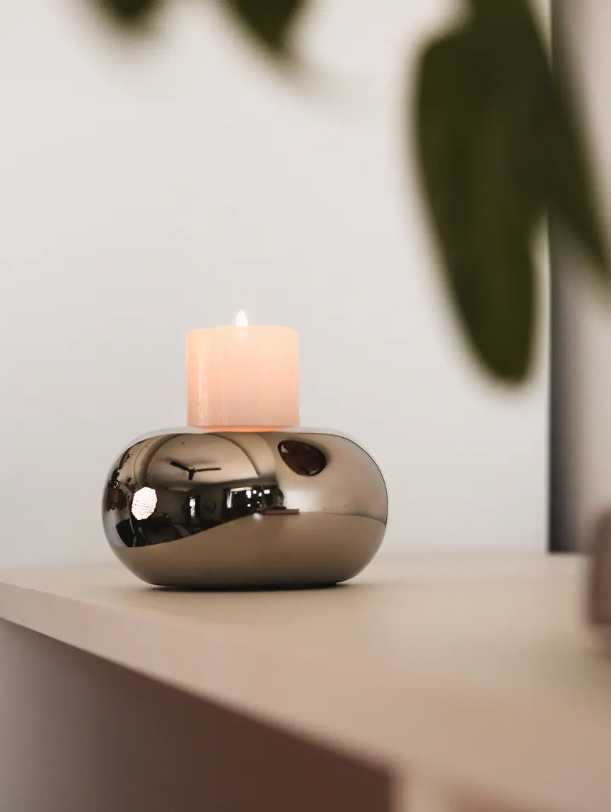 Donut Chrome Candle Holder with a white pillar candle, placed on a neutral-toned shelf.