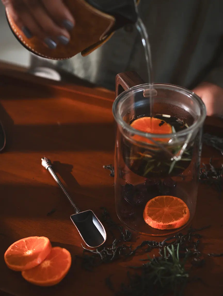 Vintage Spoon placed beside a glass teapot with dried oranges and tea leaves.