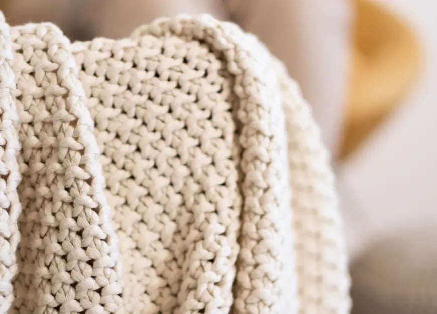 Close-up of the off-white Alpine Cotton Knitted Throw, highlighting its chunky knit pattern and soft texture.