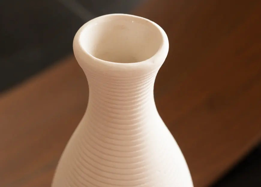 Close-up of the Contour Ceramic Vase – White, highlighting its ribbed texture and flared opening.
