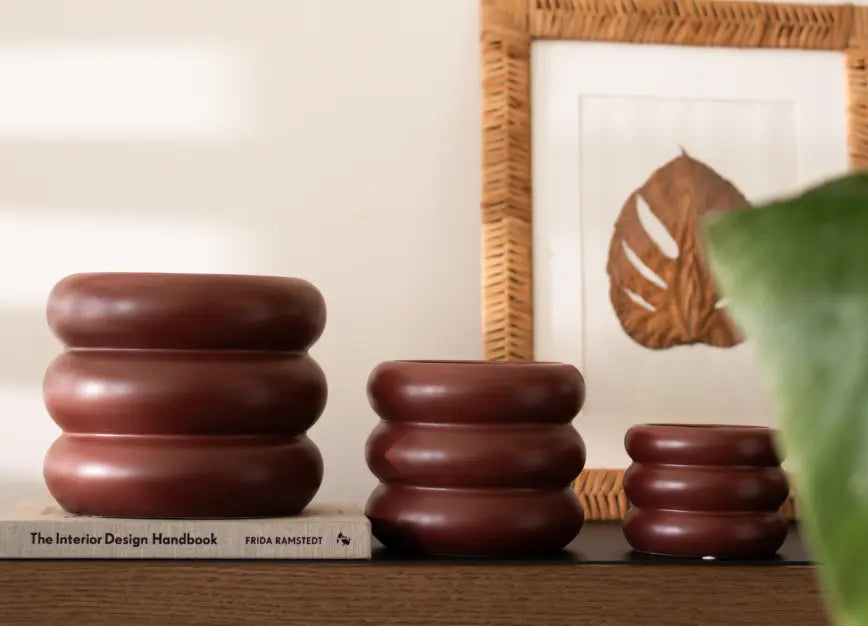 Set of three Orbit Planters - Maroon in varying sizes on a wooden console.
