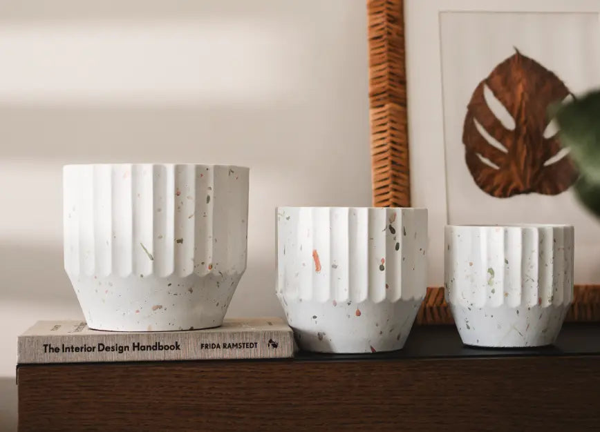 Set of three Marvellous Concrete Planters - White in different sizes, displayed on a wooden surface with books.