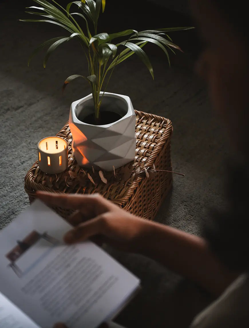 Diamond Ceramic Planter in white, styled on a woven basket with a candle, creating a cozy ambiance.