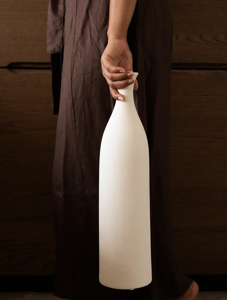 Tall Contour Ceramic Vase elegantly held upside down, emphasizing its sculptural form.