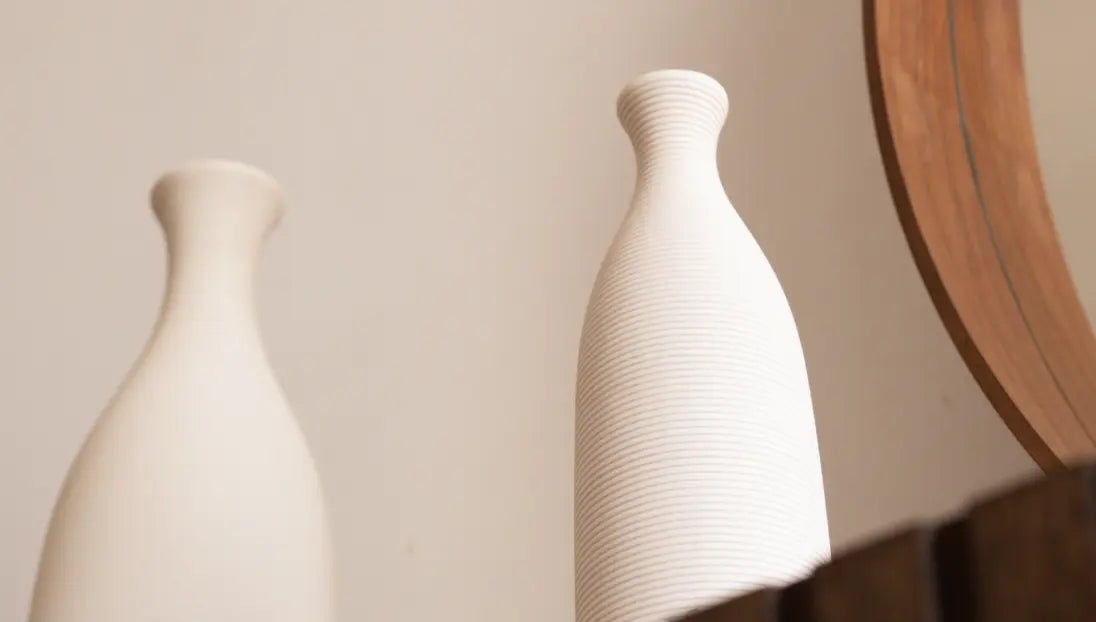 Two Contour Ceramic Vases – White, placed against a neutral background with a round wooden mirror.