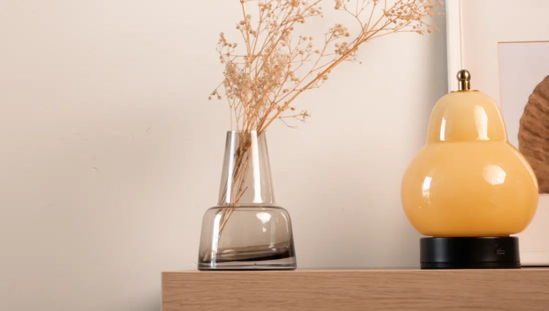 Translucent smoky Pitcher glass vase with a sturdy base, holding dried flowers against a soft background.