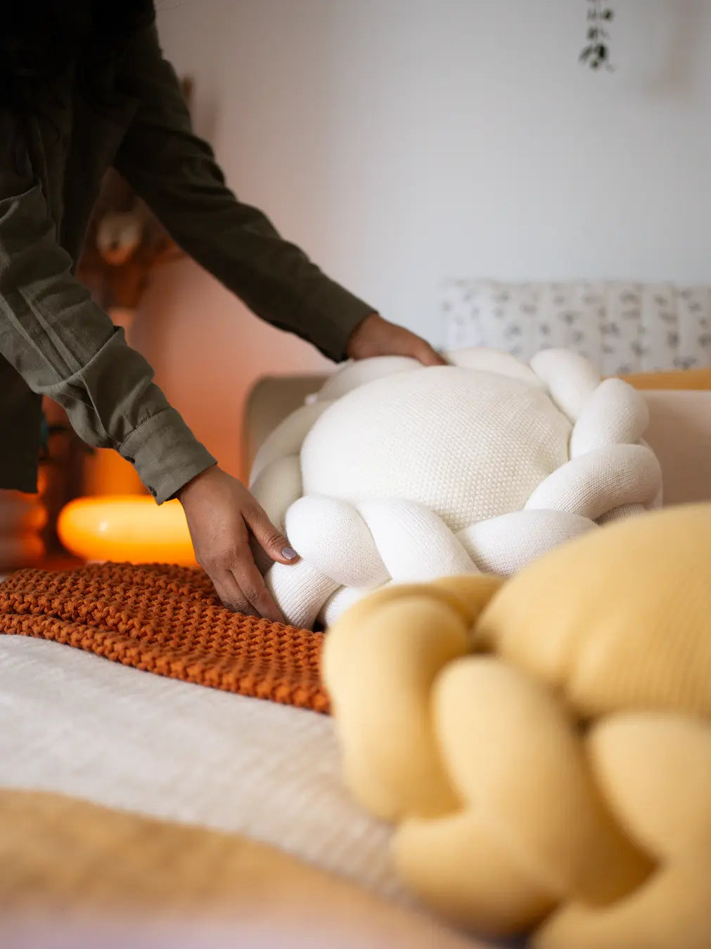 White Halo Nest Cushion placed on a bed, complementing a warm, cozy setup with soft furnishings.