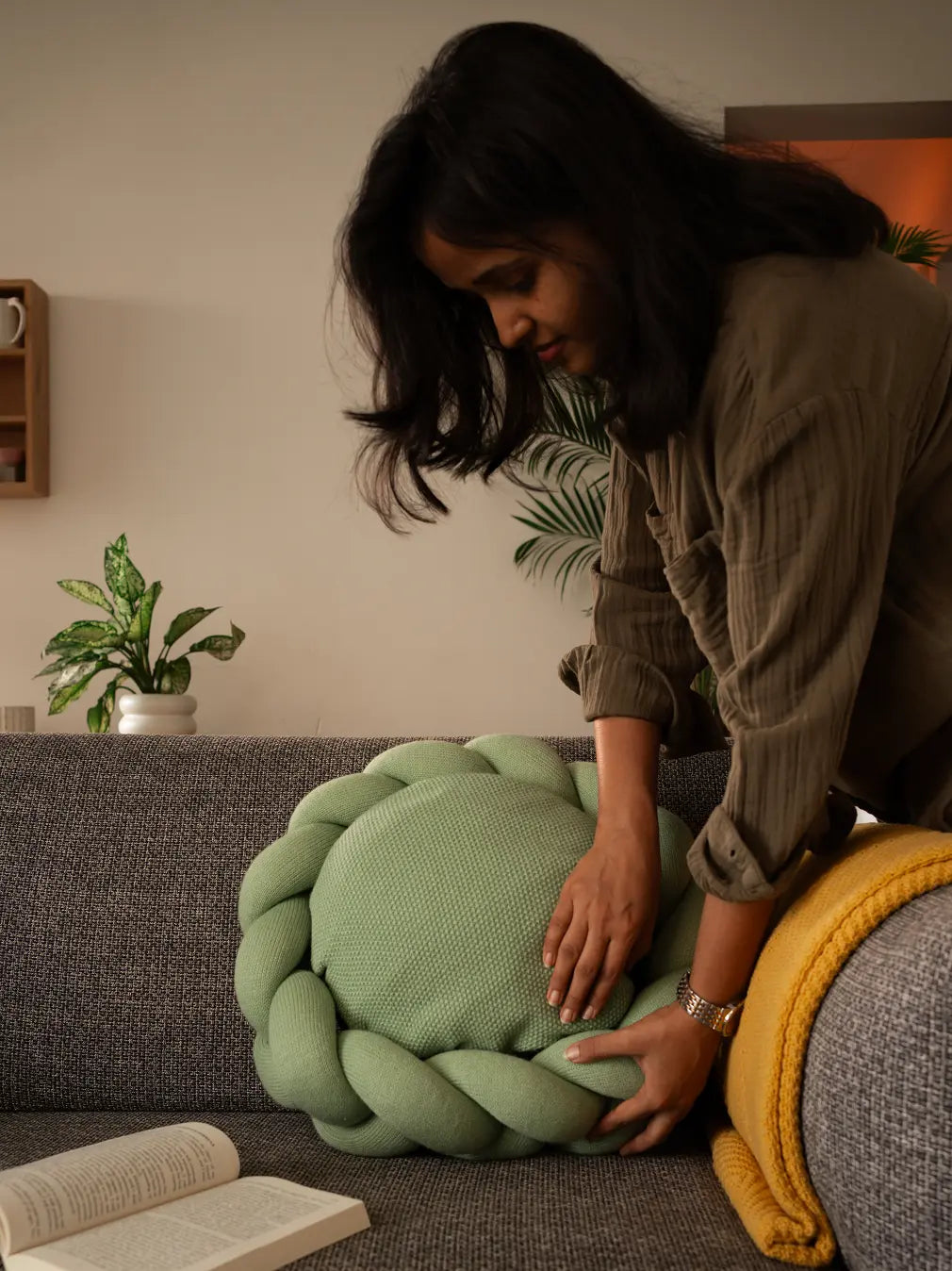 Woman styling Gharko Halo Nest Cushion on a grey couch