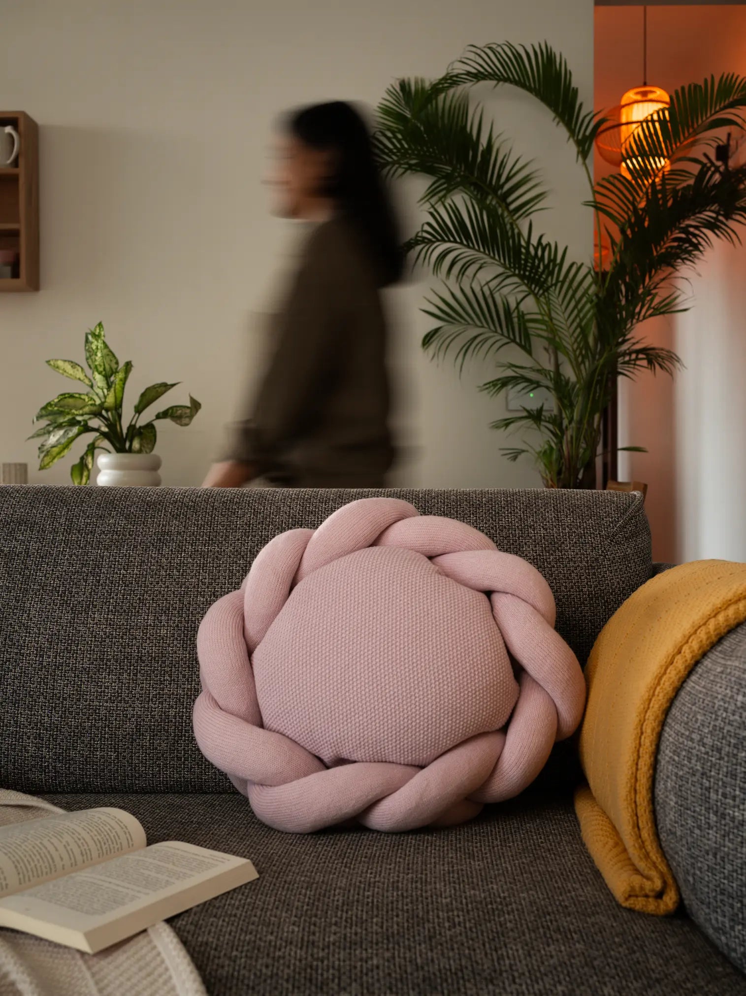Gharko pink nest cushion styled on grey sofa with yellow throw blanket