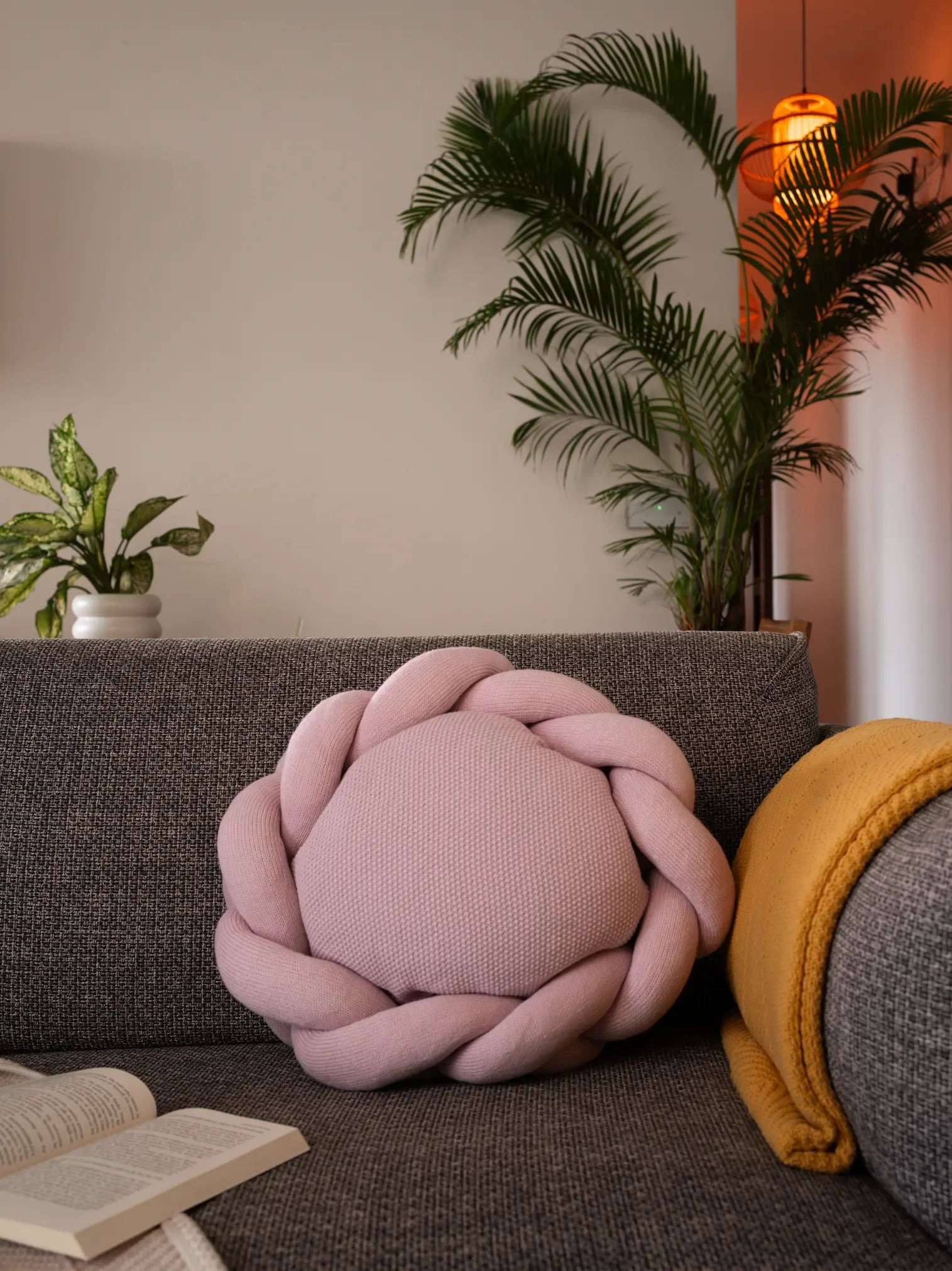 Pink braided cushion by Gharko styled with open book and indoor plants