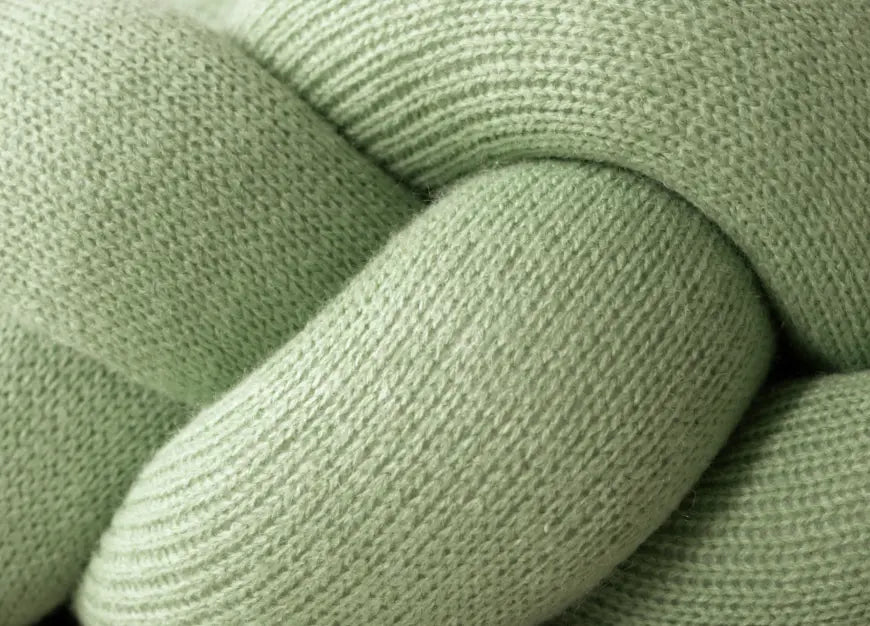 Close-up of soft knitted texture on braided edge of Halo Nest Cushion in green