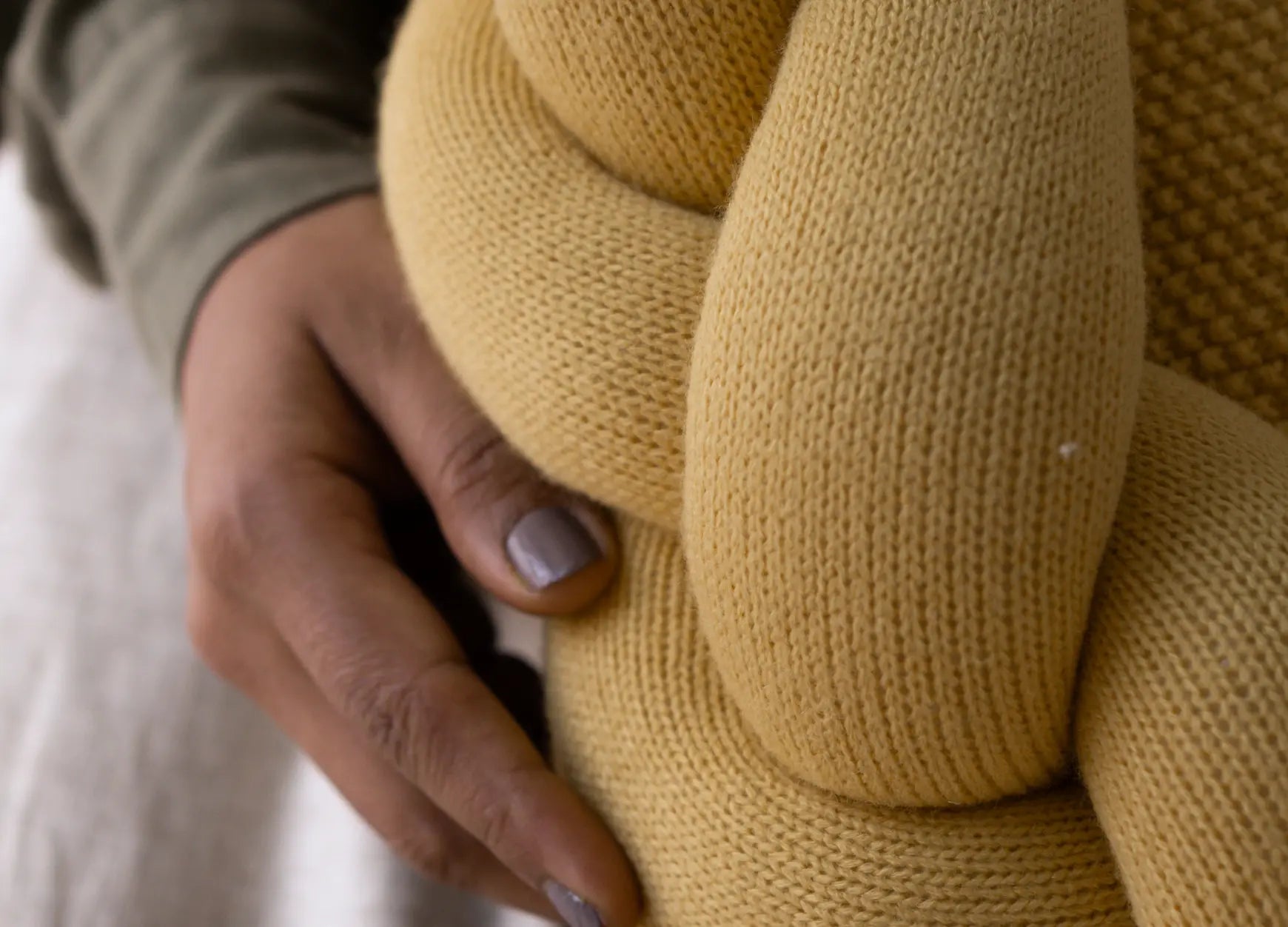 Close-up of braided knit ring on yellow round cushion with soft knit texture
