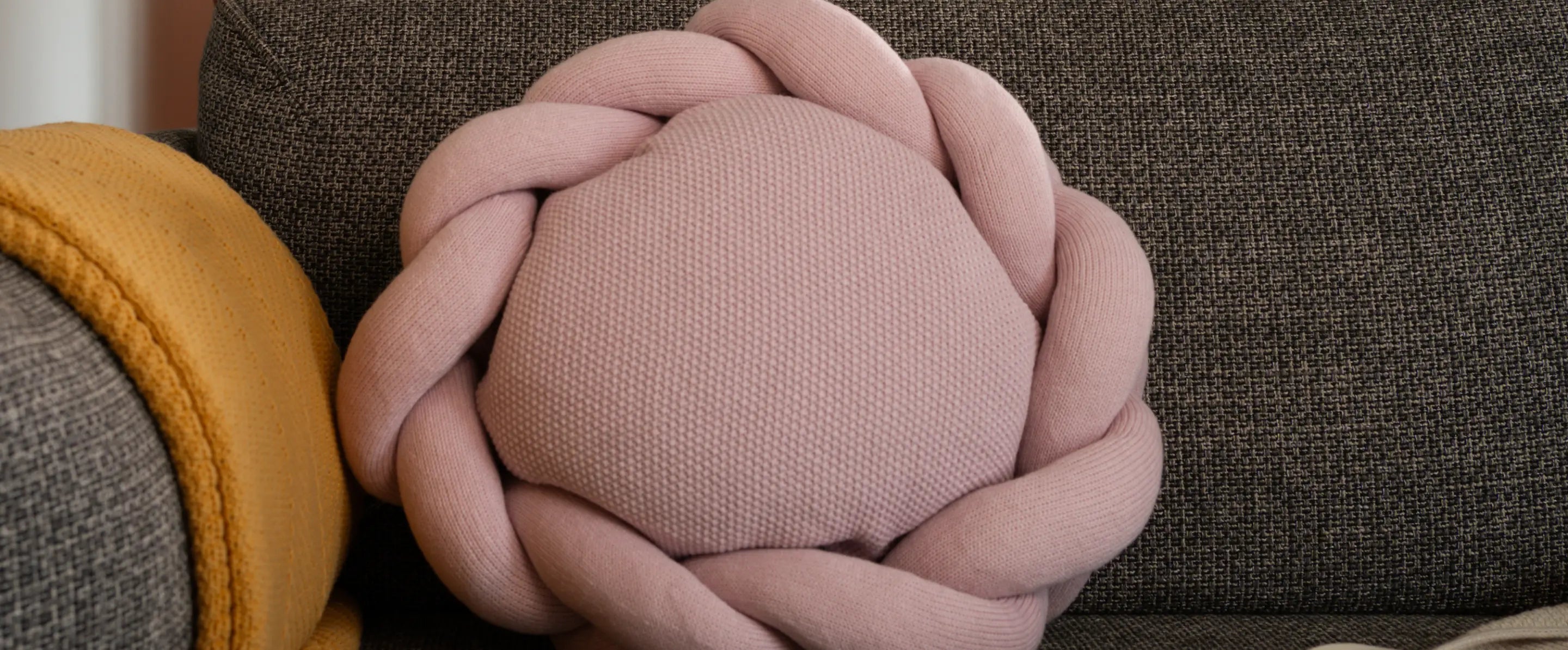 Soft pink braided round cushion on grey sofa – Gharko Halo Nest Cushion