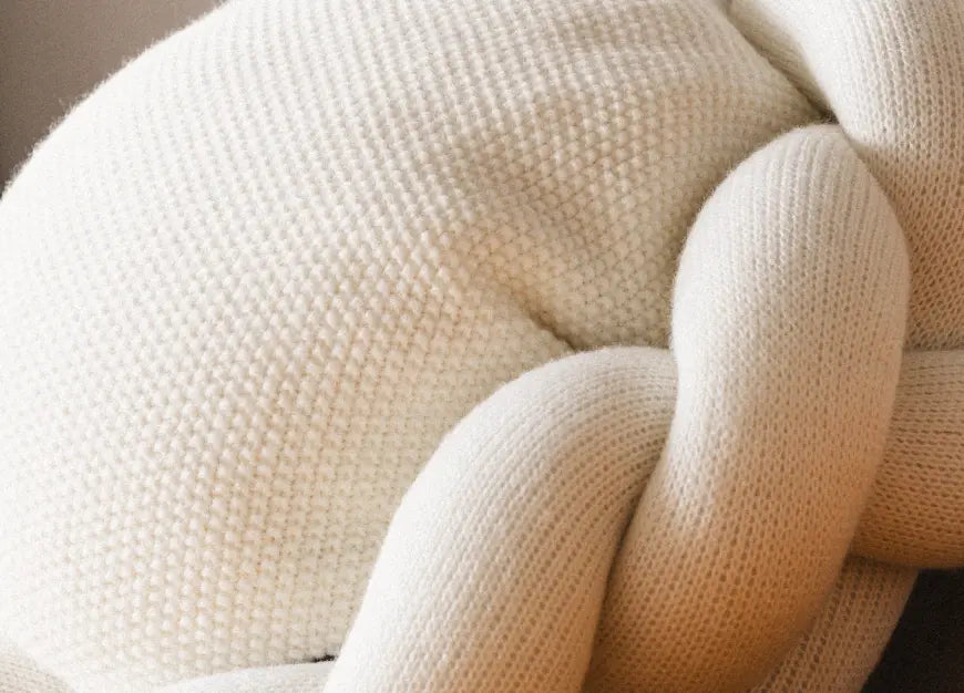 Close-up of cotton knit texture and braided edge on white Halo Nest Cushion.