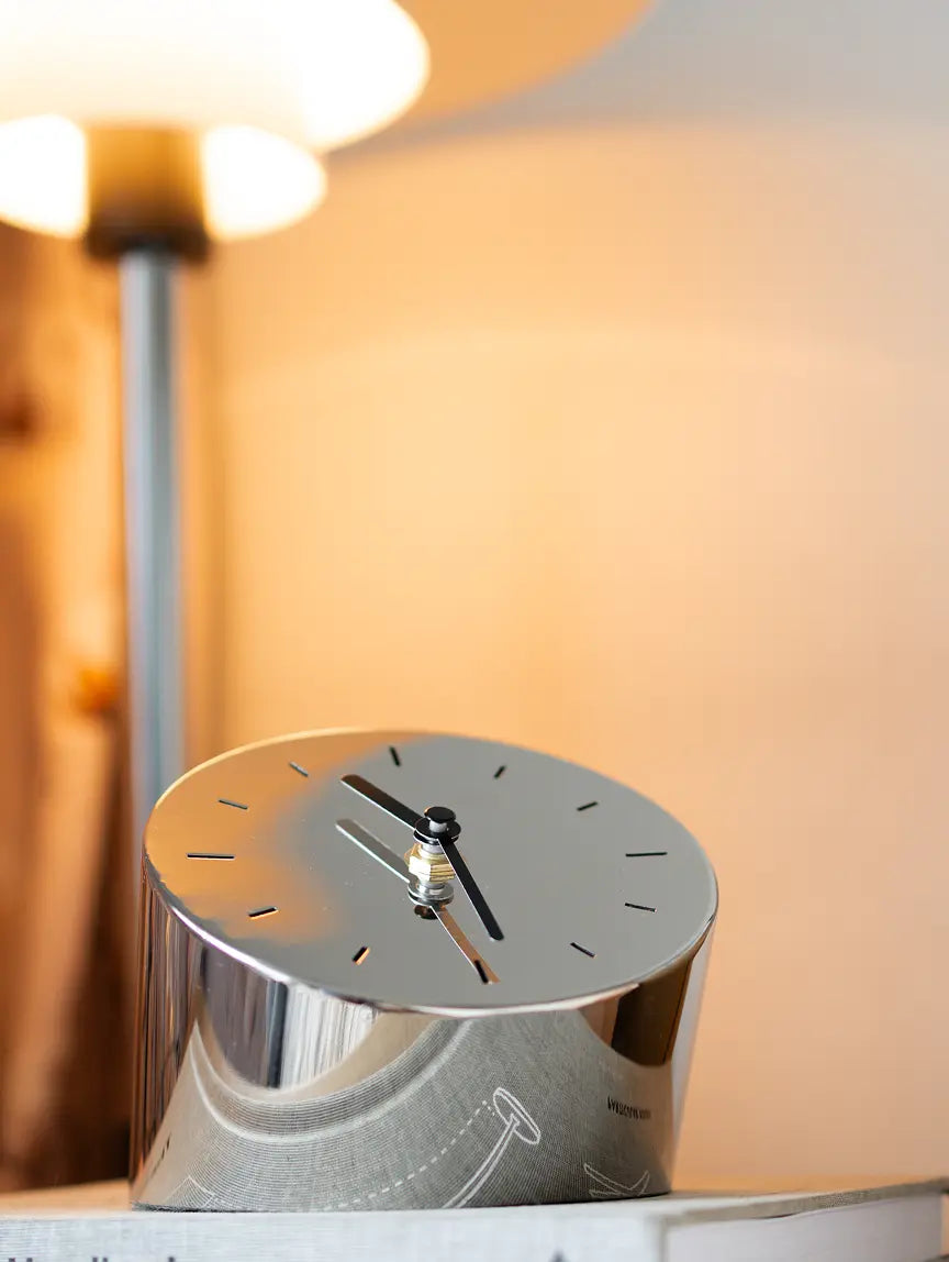 Silver metal table clock with matte black dial styled near lamp for warm ambient decor