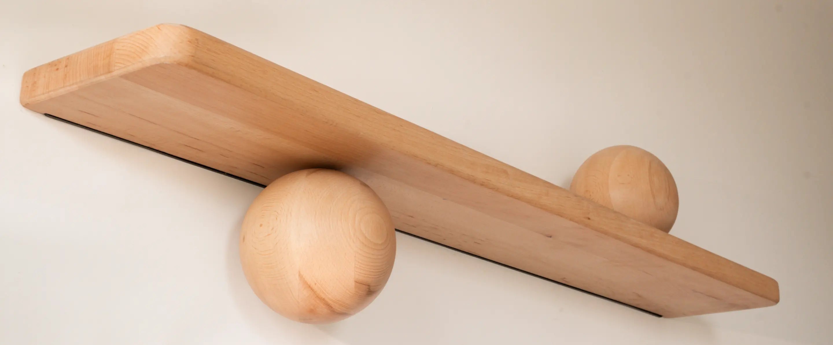 Wooden shelf with two wooden spheres on a plain background