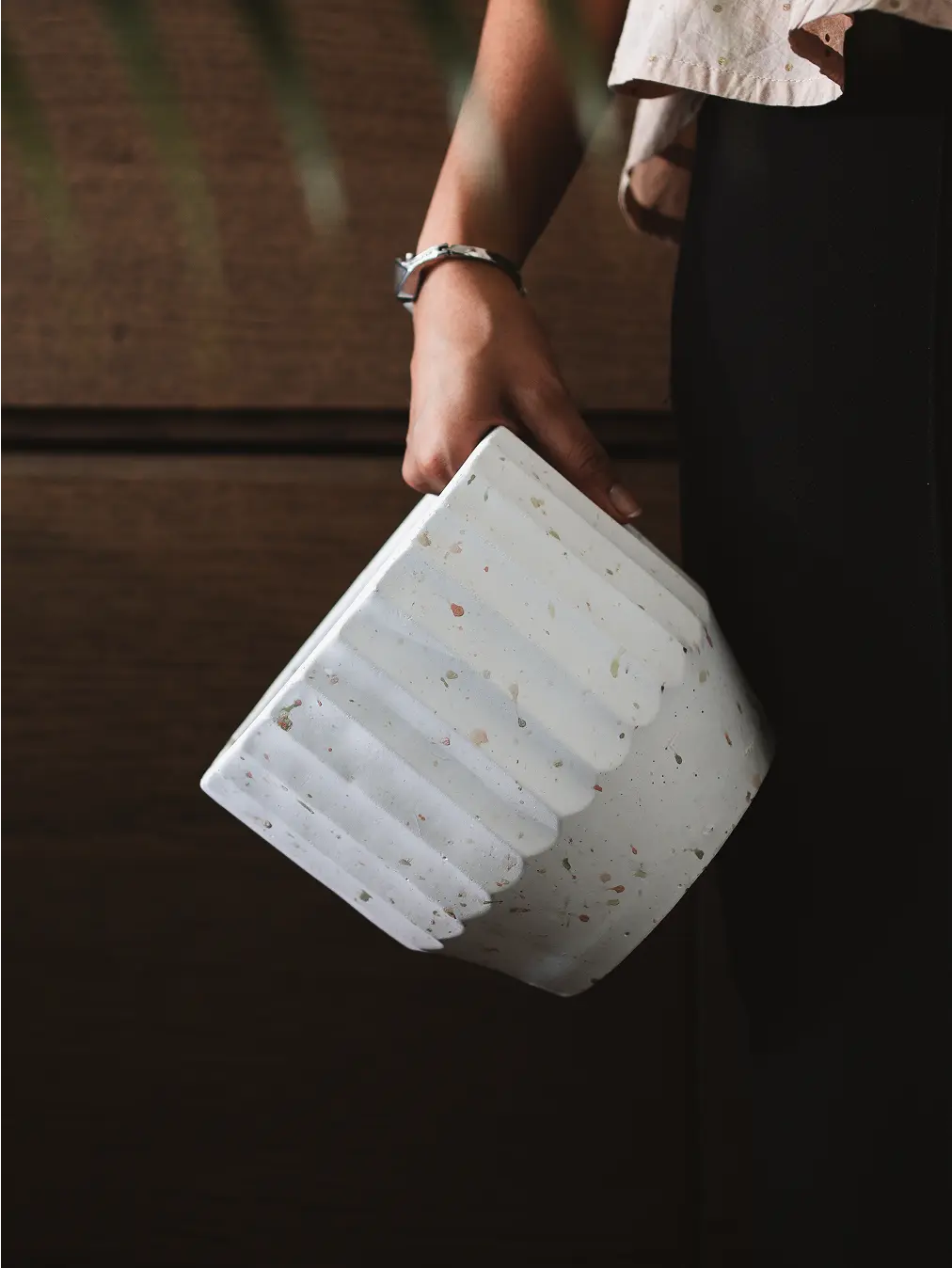 Close-up of a person holding the Marvellous Concrete Planter - White, highlighting its fluted design and speckled texture.
