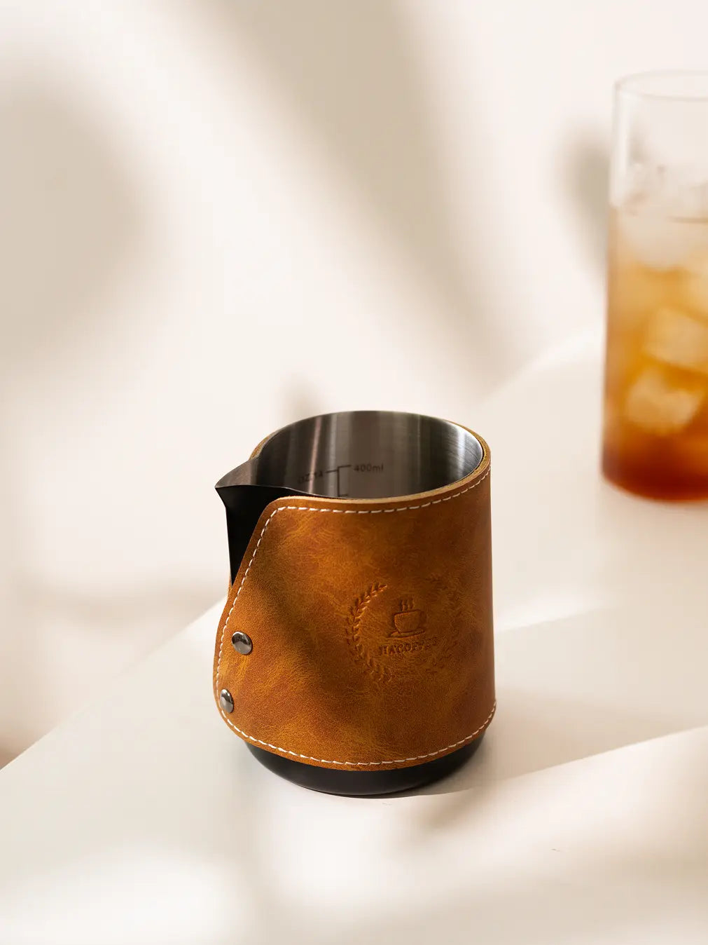 Brista Milk Pitcher with a leather wrap, stainless steel interior, and precise spout for latte art.