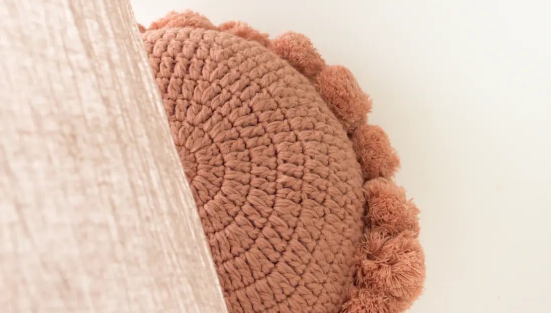 Round pink textured pillow on a white background