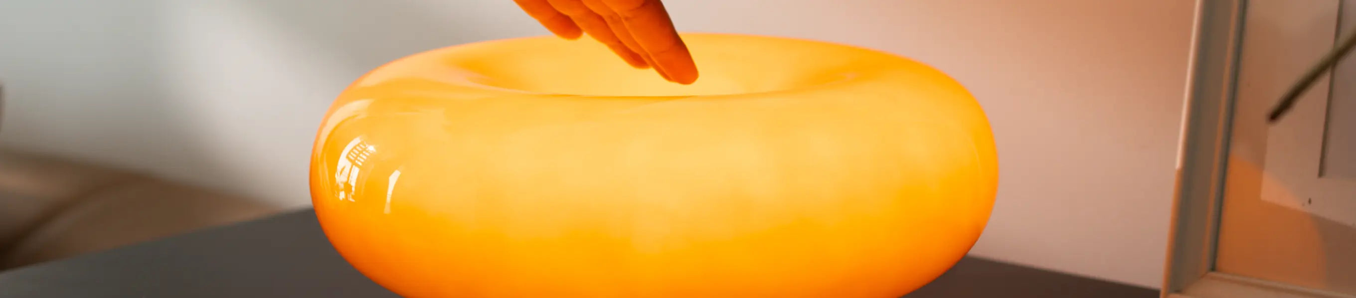 Touch control orange lamp casting soft warm light on a wooden surface in a cozy room.