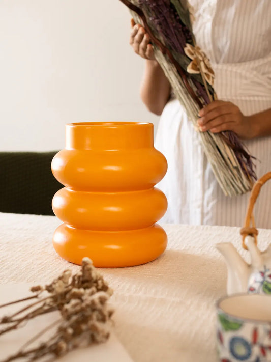 Orbit Ceramic Vase – Orange, with a sculptural bubbled design, placed on a dining table.