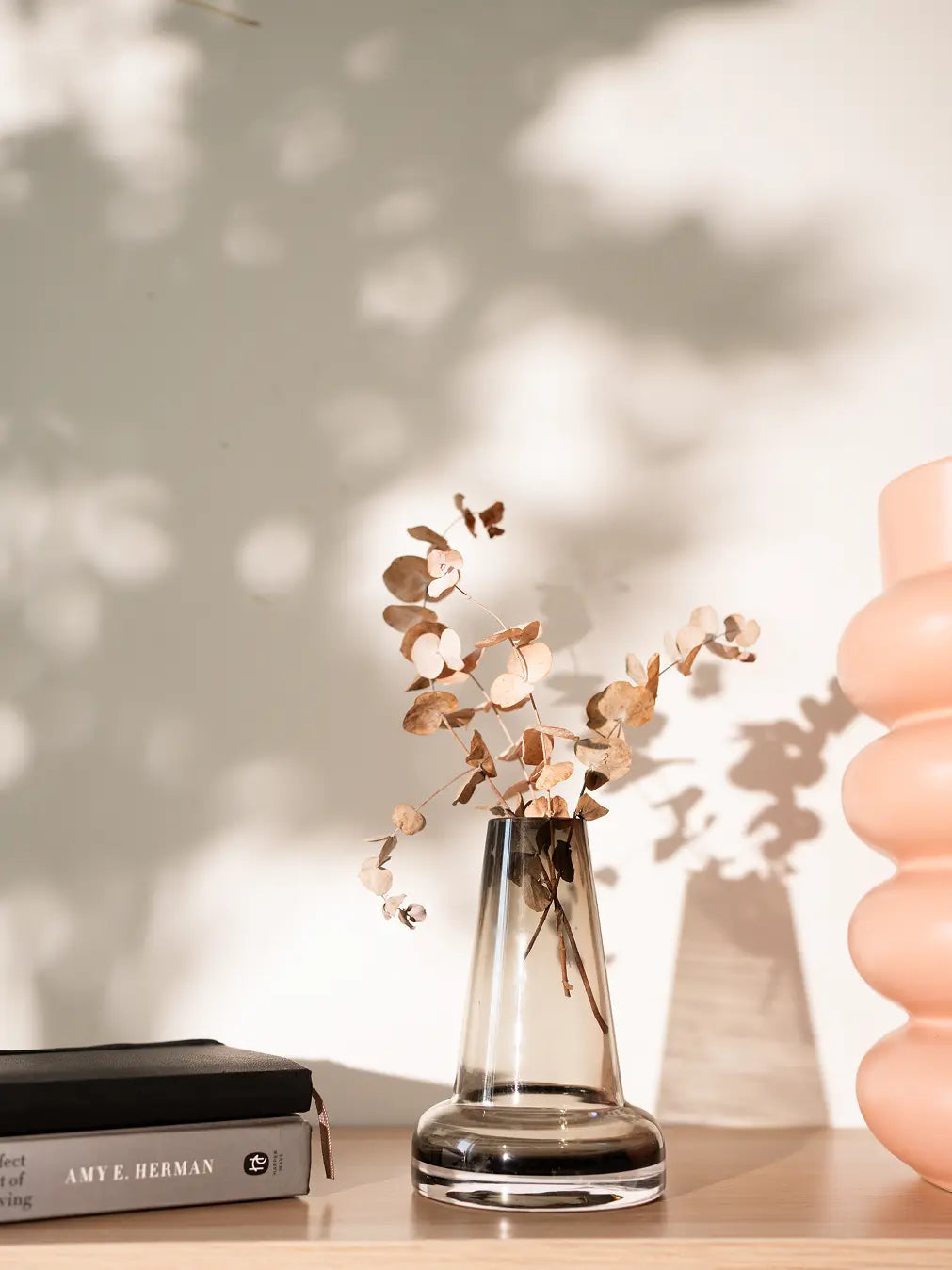 Smoky Pitcher glass vase with a long neck, holding dried eucalyptus branches, placed on a wooden shelf.