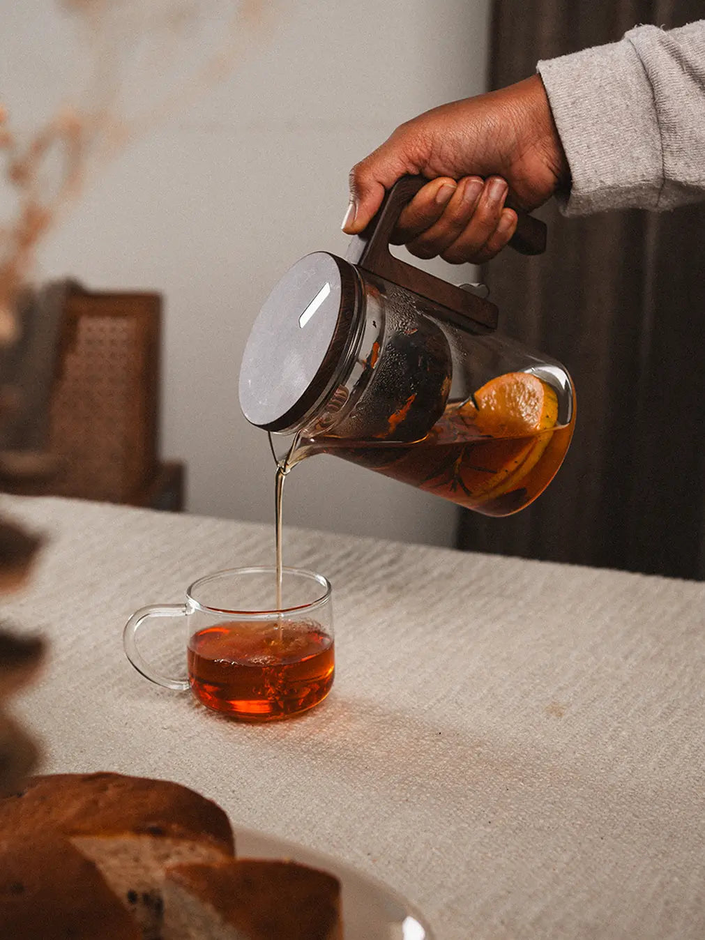 Pouring brewed tea from the Pourfect Tea Infuser, featuring a glass body and wooden handle.