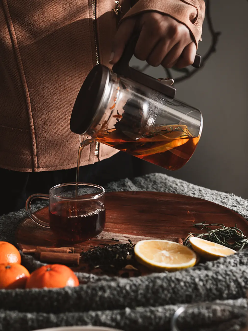 Pourfect Tea Infuser brewing tea with citrus and herbs while tea is poured into a glass cup.