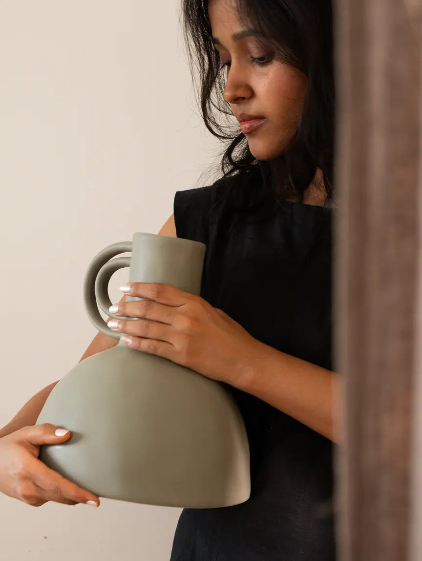 Woman holding a flower ceramic vase against a neutral background