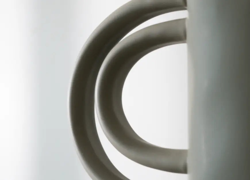 Close-up of a decorative vase with concentric circular handle on a light grey background