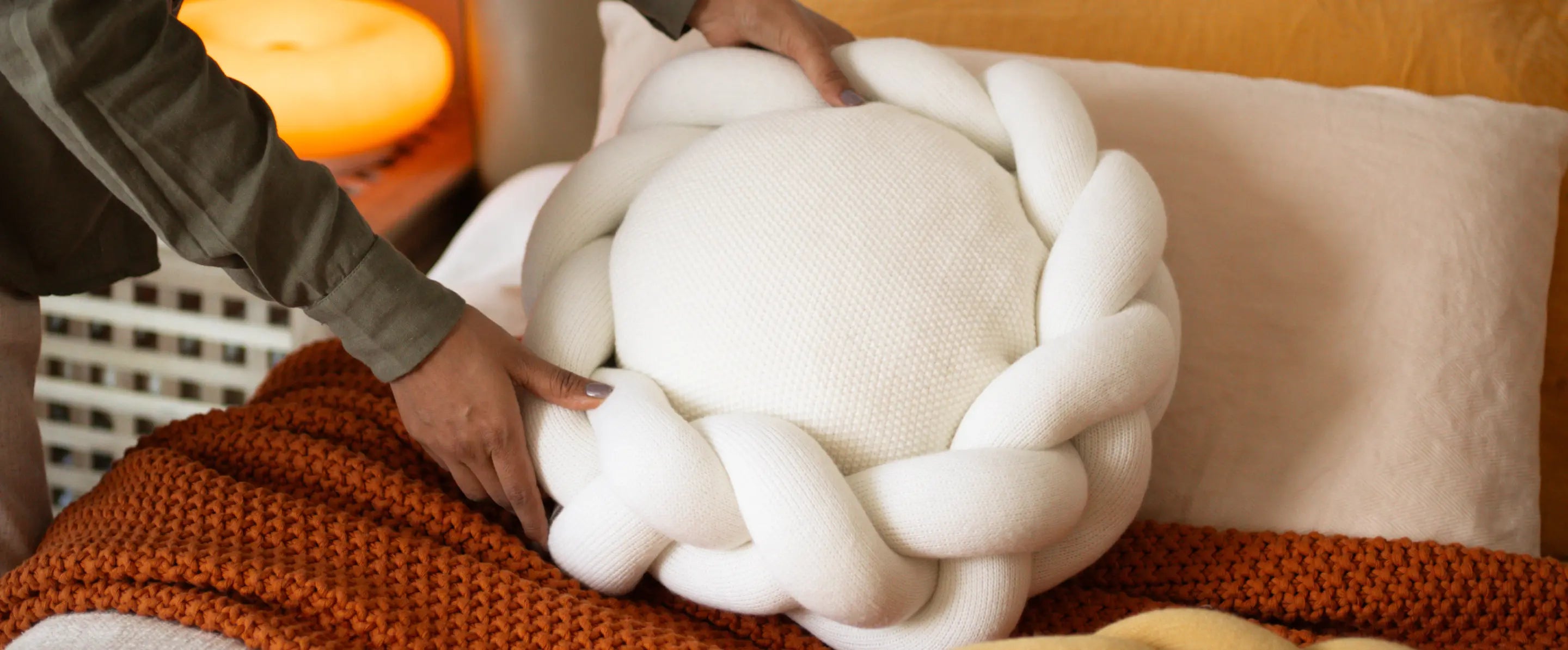 Halo Nest Cushion in white, carefully placed on a pillow, adding a soft and cozy accent to bedding.