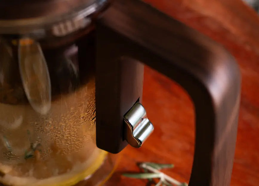 Close-up of the Pourfect Tea Infuser’s wooden handle with a stainless steel release lever for magnetic filter.