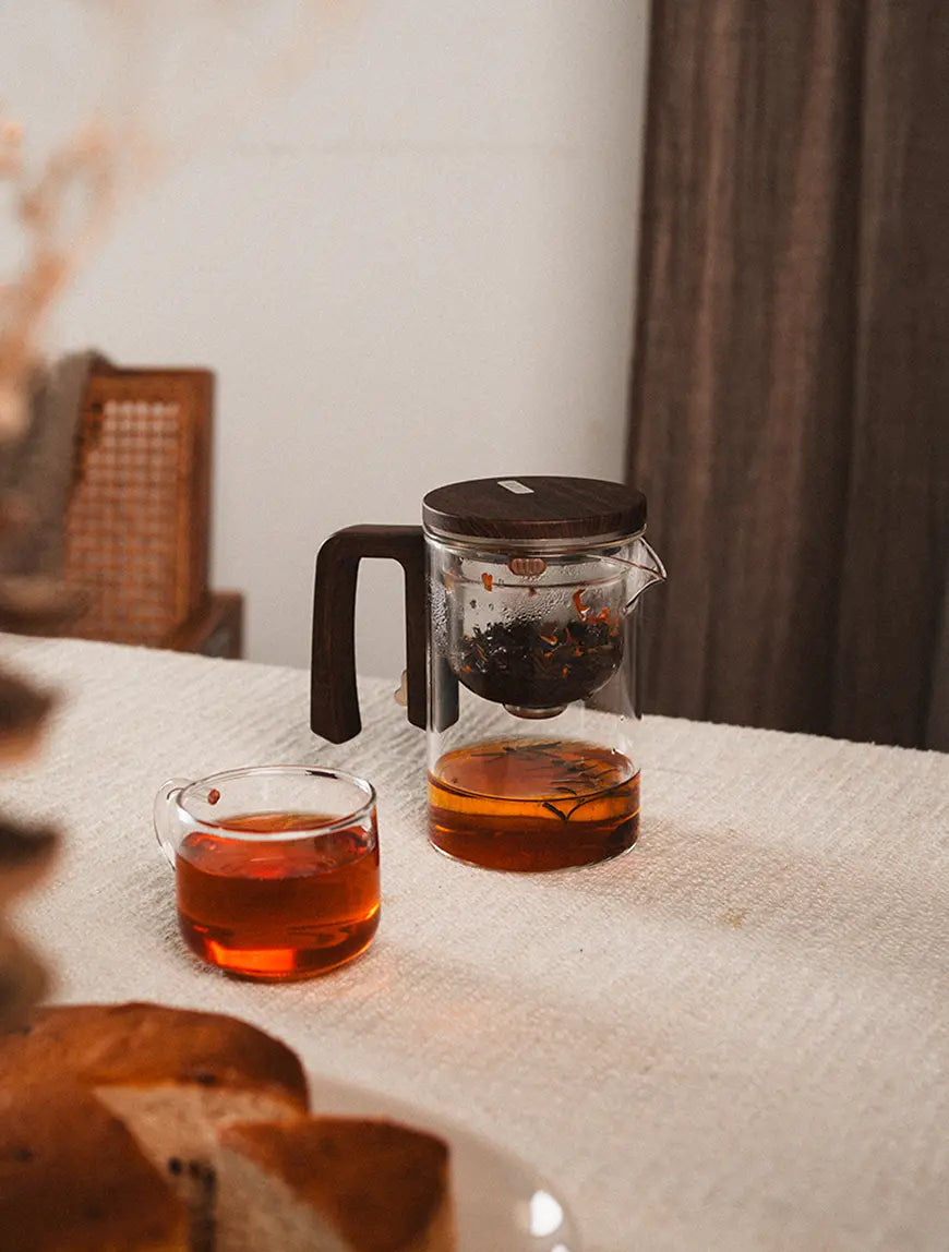 Pourfect Tea Infuser placed beside a tea cup, featuring its double-wall borosilicate glass construction.