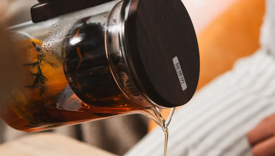Pourfect Tea Infuser pouring tea, highlighting its precision pour spout and wooden-textured lid.