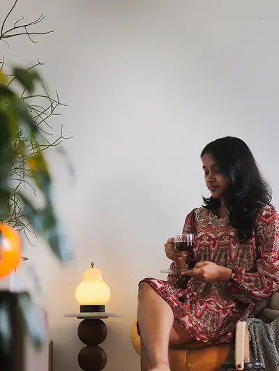Woman relaxing with coffee beside a warm table lamp – cozy modern home decor setup