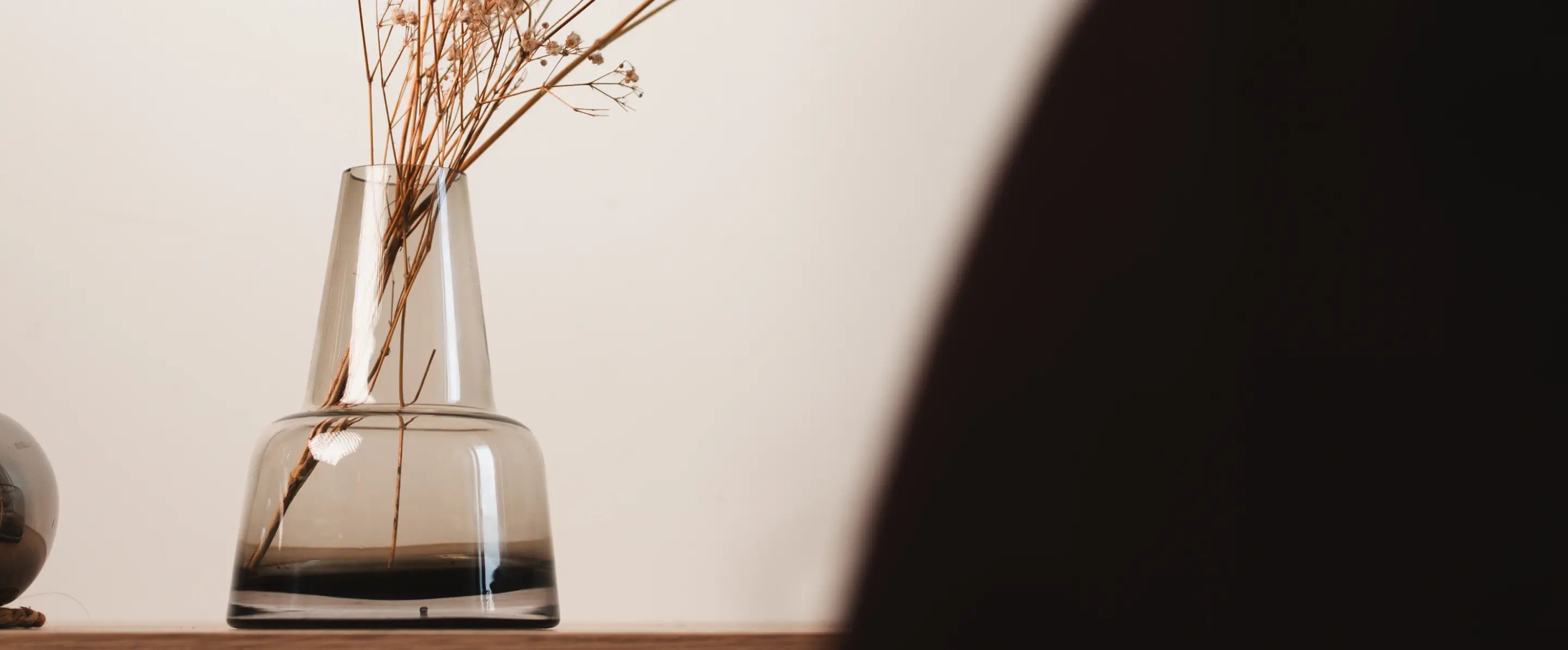 Close-up of the Pitcher Glass Vase - Medium Neck, showcasing its smooth glass curves and elegant transparency.