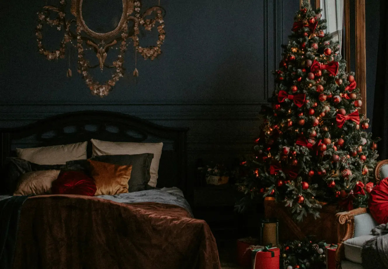 Cozy dark bedroom with layered bedding and a decorated Christmas tree, perfect inspiration for guest-ready holiday bedroom decor.